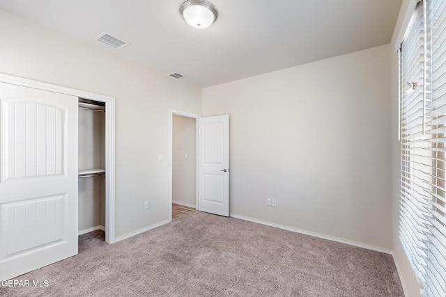unfurnished bedroom featuring a closet, carpet flooring, baseboards, and visible vents
