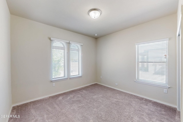 unfurnished room with carpet flooring and baseboards