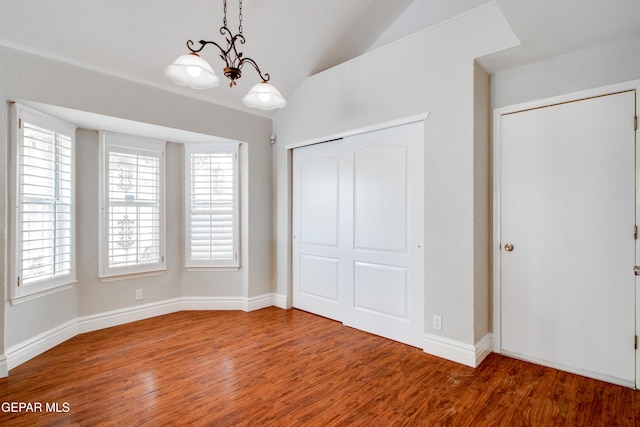 interior space featuring plenty of natural light, baseboards, vaulted ceiling, and wood finished floors
