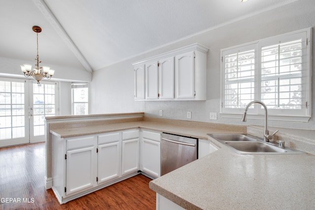kitchen featuring a peninsula, white cabinets, lofted ceiling, stainless steel dishwasher, and a sink