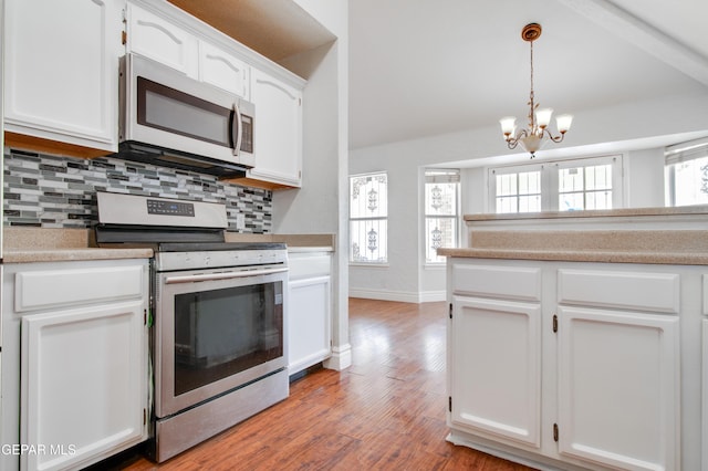 kitchen with a notable chandelier, white cabinets, stainless steel range with electric cooktop, decorative backsplash, and wood finished floors