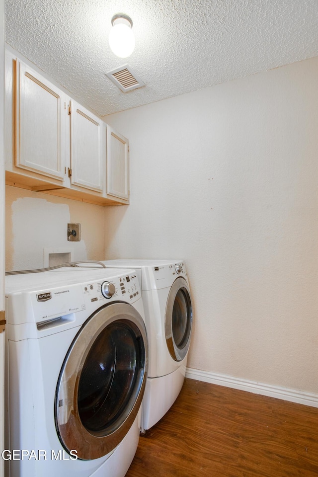 washroom featuring visible vents, separate washer and dryer, a textured ceiling, dark wood finished floors, and cabinet space