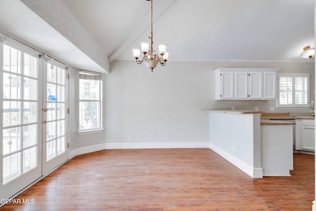 kitchen with light wood-style flooring, vaulted ceiling, white cabinets, and hanging light fixtures