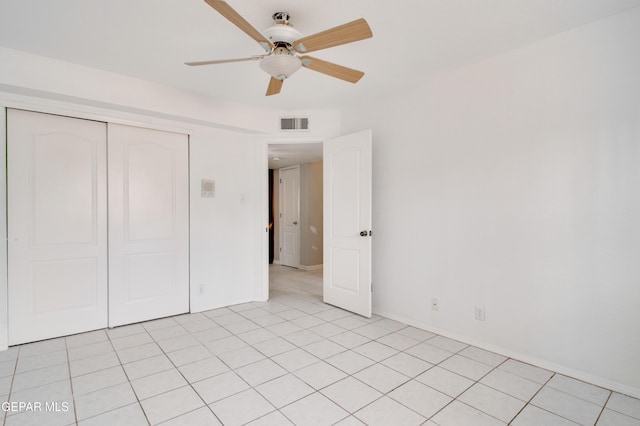 unfurnished bedroom with a closet, a ceiling fan, visible vents, light tile patterned flooring, and baseboards