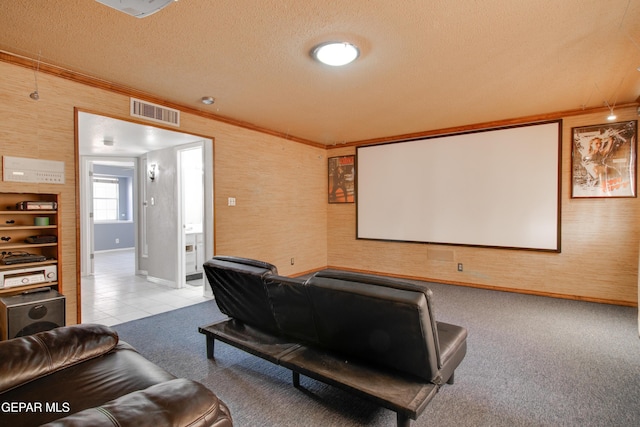 cinema room with baseboards, ornamental molding, light carpet, a textured ceiling, and visible vents