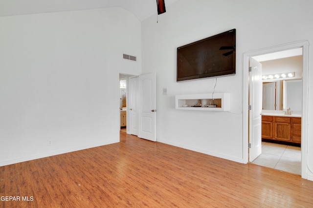 unfurnished living room featuring visible vents, baseboards, a sink, and light wood-style flooring