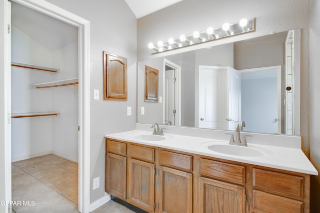 bathroom with a sink, a spacious closet, double vanity, and tile patterned flooring