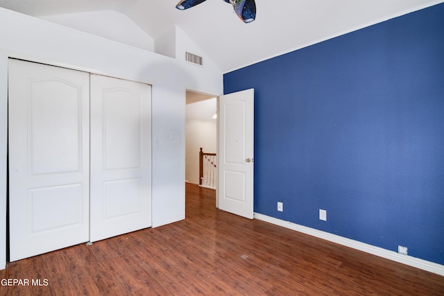 unfurnished bedroom featuring visible vents, baseboards, a closet, wood finished floors, and lofted ceiling