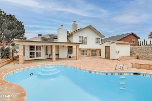 back of property with a chimney, an outdoor structure, a patio, a storage unit, and french doors