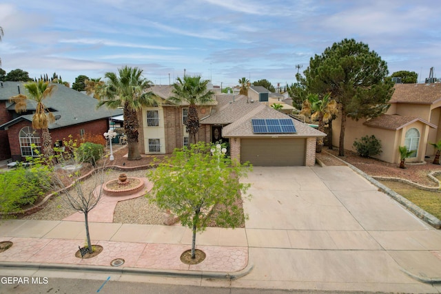 traditional home featuring concrete driveway, solar panels, and an attached garage