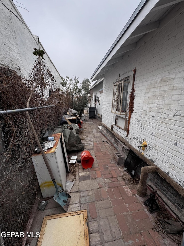 view of property exterior with brick siding and a patio