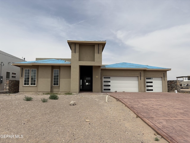 11345 Ardelle Ave, El Paso, TX 79936 - prairie-style home featuring an attached garage, metal roof, decorative driveway, and stucco siding