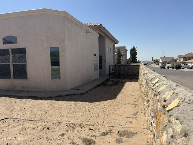 view of side of home with stucco siding and a tile roof