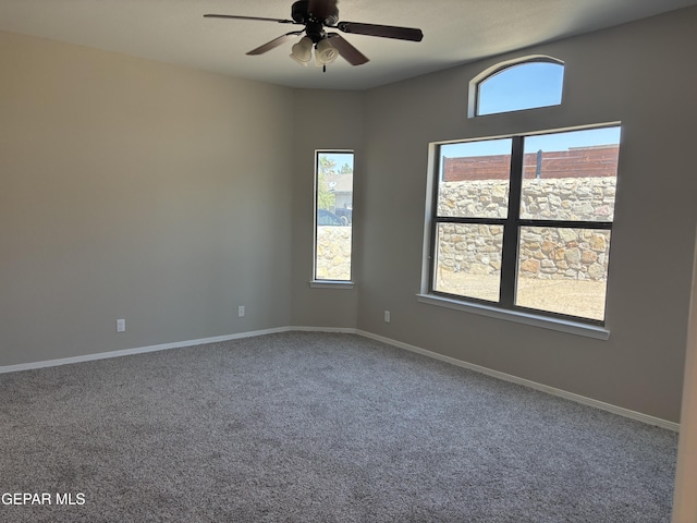 carpeted empty room with baseboards and a ceiling fan