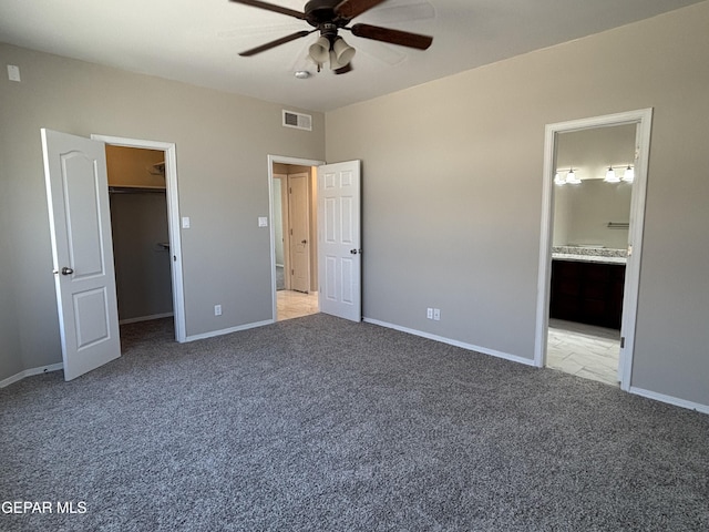 unfurnished bedroom featuring visible vents, baseboards, a spacious closet, and light carpet