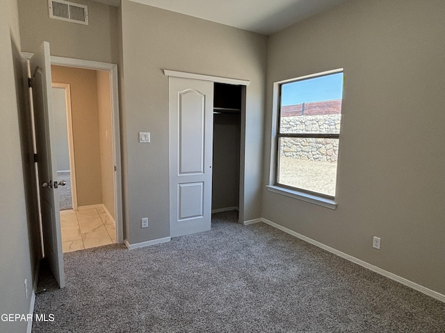 unfurnished bedroom with a closet, baseboards, carpet flooring, and visible vents