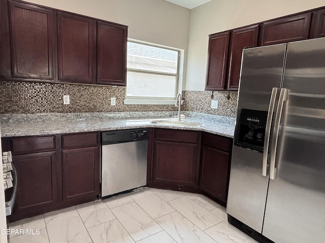 kitchen with a sink, light stone countertops, stainless steel appliances, and marble finish floor