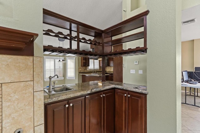 5628 Buckley Dr, El Paso, TX 79912 - kitchen featuring light tile patterned floors, light stone countertops, dark brown cabinetry, visible vents, and a sink