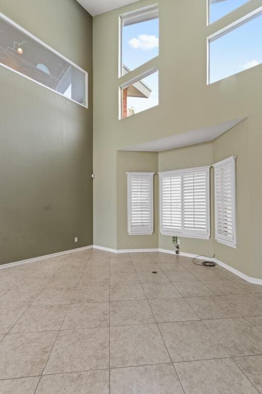 5628 Buckley Dr, El Paso, TX 79912 - empty room featuring tile patterned floors, a towering ceiling, and baseboards