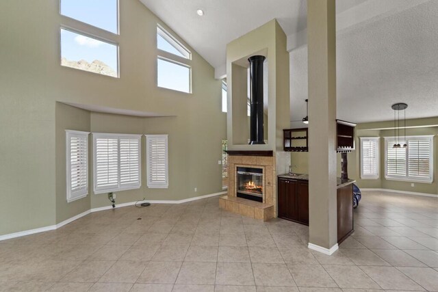 5628 Buckley Dr, El Paso, TX 79912 - unfurnished living room featuring high vaulted ceiling, a fireplace, light tile patterned floors, and a healthy amount of sunlight