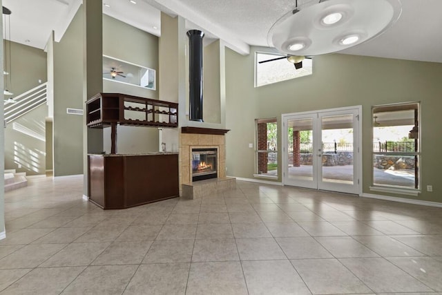 5628 Buckley Dr, El Paso, TX 79912 - unfurnished living room with baseboards, tile patterned flooring, ceiling fan, high vaulted ceiling, and a tile fireplace