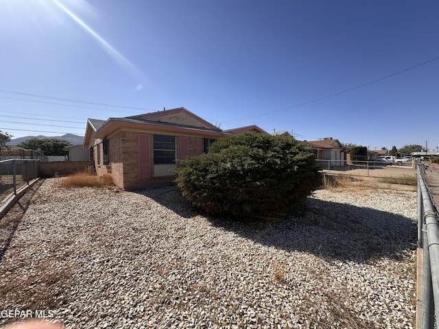 view of property exterior with fence and brick siding
