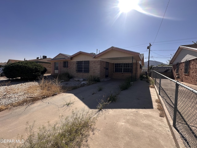 single story home with driveway, fence, and brick siding