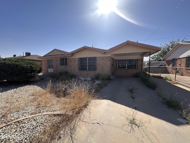 single story home featuring brick siding, fence, a carport, and driveway