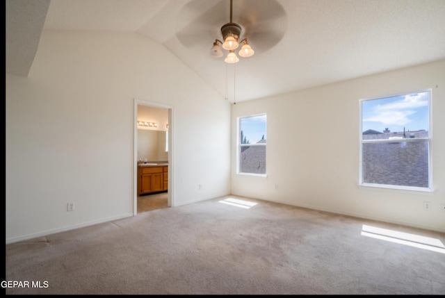 interior space with baseboards, vaulted ceiling, connected bathroom, carpet floors, and a sink