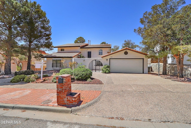 mediterranean / spanish house featuring a garage, driveway, a tiled roof, and stucco siding