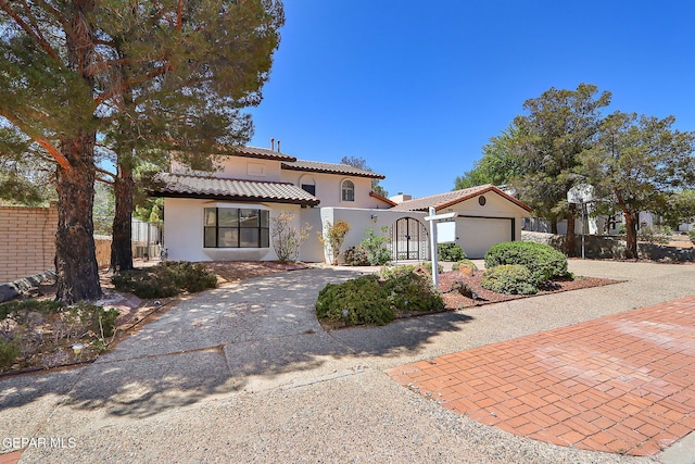 mediterranean / spanish house with fence, a tiled roof, stucco siding, driveway, and a garage