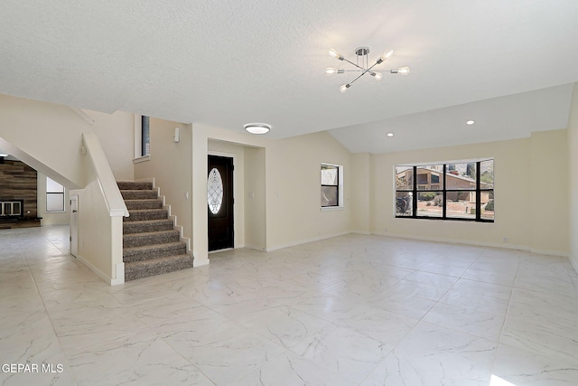 entryway with lofted ceiling, marble finish floor, baseboards, a chandelier, and stairs