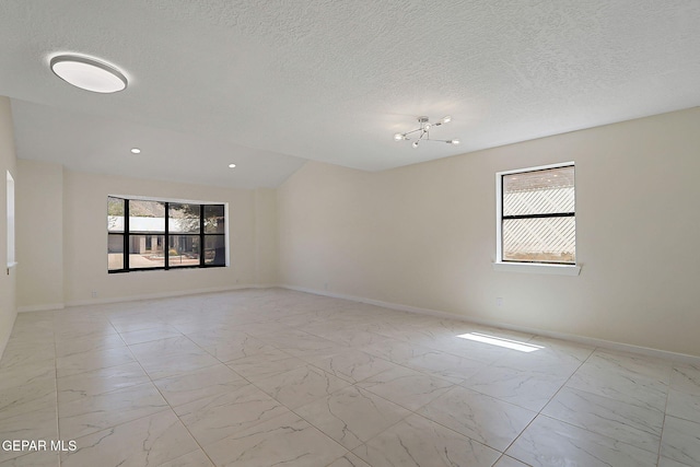 spare room featuring marble finish floor, baseboards, and a textured ceiling