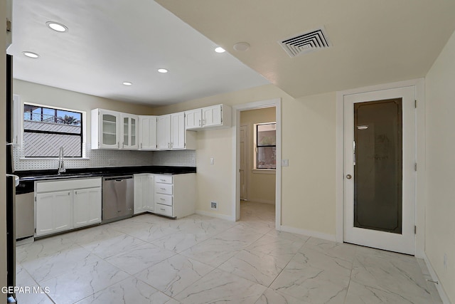 kitchen with stainless steel dishwasher, dark countertops, baseboards, white cabinetry, and visible vents