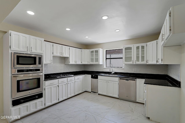 kitchen with a sink, a warming drawer, marble finish floor, white cabinets, and appliances with stainless steel finishes
