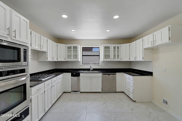 kitchen with stainless steel appliances, marble finish floor, a sink, and glass insert cabinets