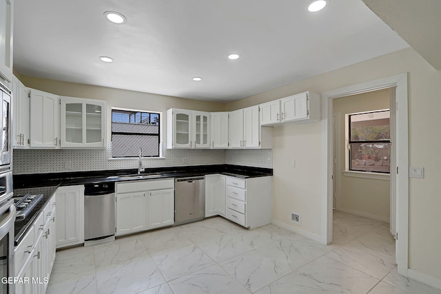 kitchen with stainless steel dishwasher, baseboards, a sink, and marble finish floor
