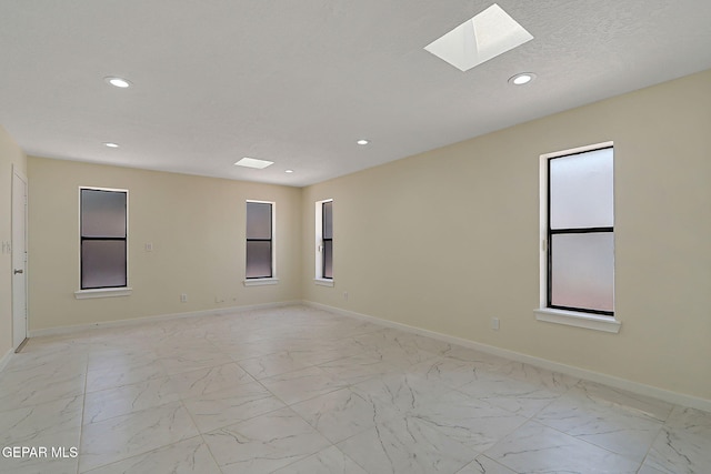unfurnished room featuring recessed lighting, a skylight, and marble finish floor