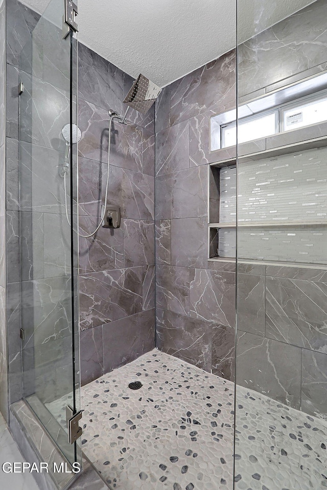 bathroom featuring a textured ceiling and tiled shower