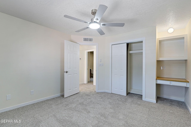 unfurnished bedroom featuring carpet flooring, a textured ceiling, and visible vents
