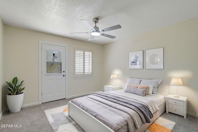 carpeted bedroom with a textured ceiling, baseboards, and ceiling fan
