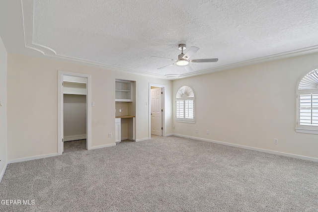 unfurnished bedroom with ceiling fan, light carpet, a textured ceiling, and baseboards