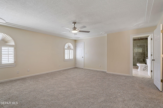 carpeted empty room with baseboards, a ceiling fan, and a textured ceiling