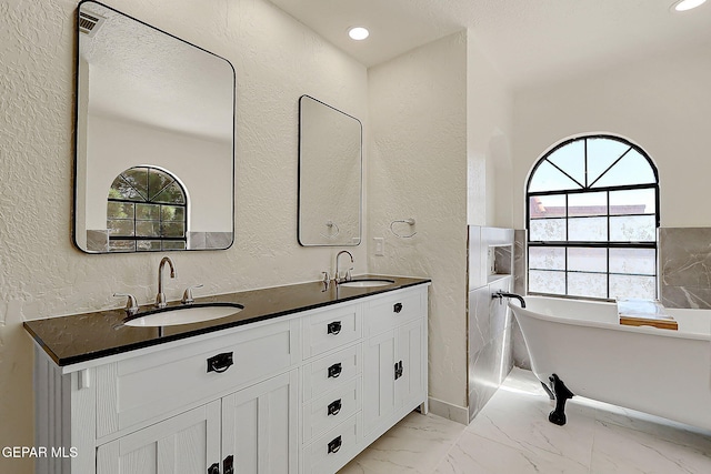 bathroom featuring double vanity, a textured wall, marble finish floor, and a sink