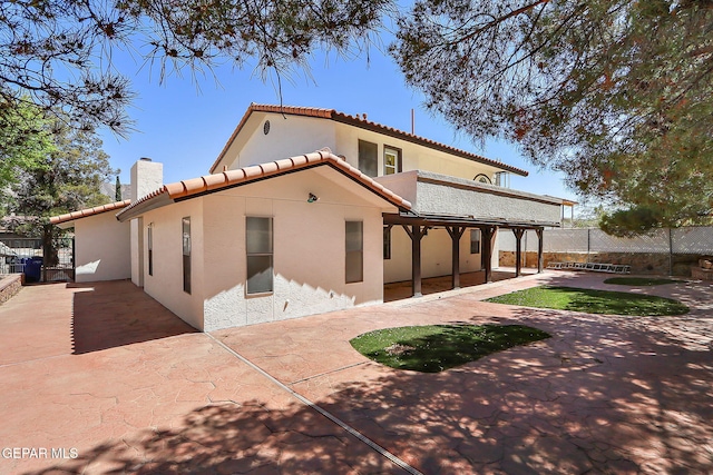 exterior space featuring a tile roof, a chimney, fence, a patio, and stucco siding