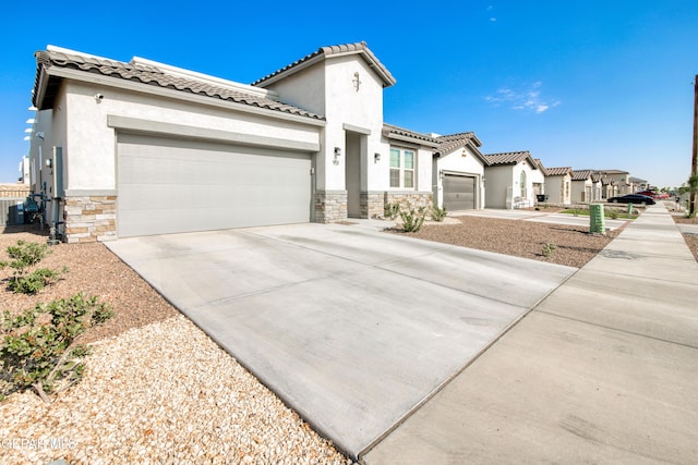951 Airship Pl, El Paso, TX 79928 - mediterranean / spanish-style home featuring stone siding, a garage, concrete driveway, stucco siding, and a tiled roof