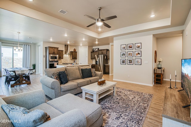 951 Airship Pl, El Paso, TX 79928 - living room with a chandelier, ceiling fan, light wood-style floors, a raised ceiling, and baseboards
