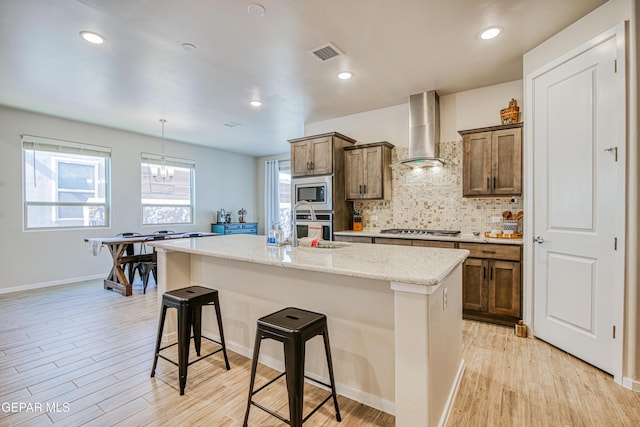 951 Airship Pl, El Paso, TX 79928 - kitchen with wall chimney range hood, a breakfast bar, decorative backsplash, light wood-style flooring, and recessed lighting