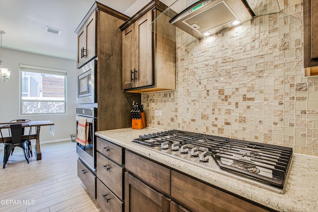 951 Airship Pl, El Paso, TX 79928 - kitchen with stainless steel appliances, baseboards, decorative backsplash, light stone countertops, and range hood