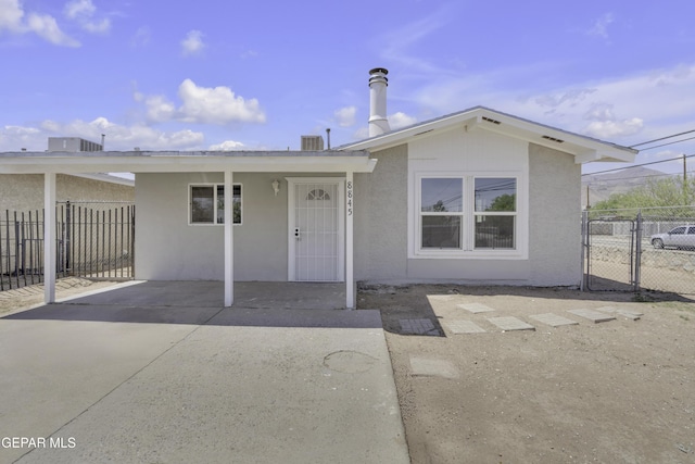 ranch-style house with stucco siding, a gate, and fence